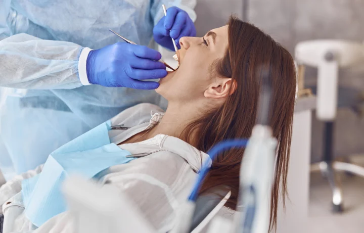professional doctor is doing tooth surgery happy caucasian woman modern dental cabinet
