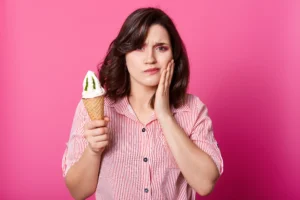 attractive lady holds fresh milk ice cream keeps hand cheek has toothache brunette sufers from sensitive tooth disease eats cold sundae stands pink wall