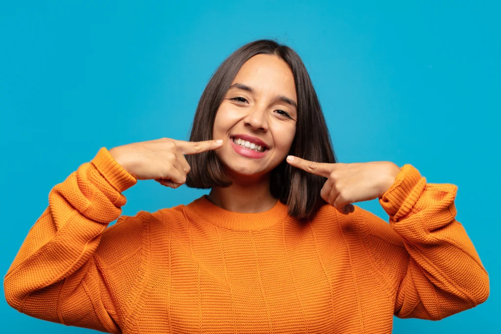 young woman smiling confidently pointing own broad smile