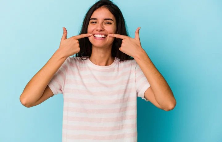 young caucasian woman isolated blue background smiles pointing fingers mouth 1